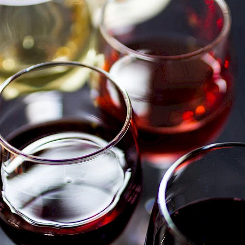 A close-up of four wine glasses filled with red and white wine, captured from above, showing rich colors and reflective glass surfaces.