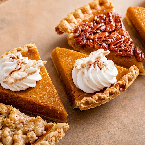 Whipped-cream-topped caramel pecan tart slices on parchment paper.