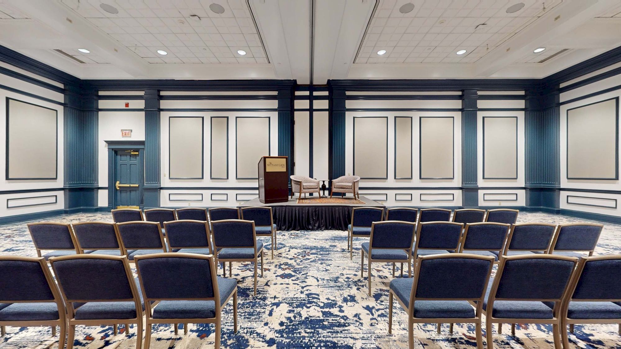 A conference or meeting room set up for a presentation, with chairs facing a stage and podium.