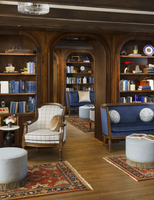 A luxurious library lounge with built-in wooden bookcases, cozy seating, and elegant rugs creating a refined, inviting reading nook.