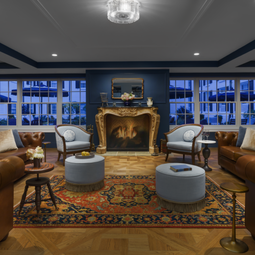 A cozy caf&eacute; or bar with warm lighting, wooden shelves, and a large guitar display; shelves filled with bottles and decor behind a central seating area.