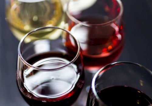 A close-up of four wine glasses filled with red and white wine, captured from above, showing rich colors and reflective glass surfaces.