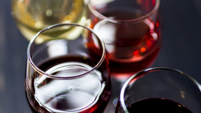 A close-up of four wine glasses filled with red and white wine, captured from above, showing rich colors and reflective glass surfaces.